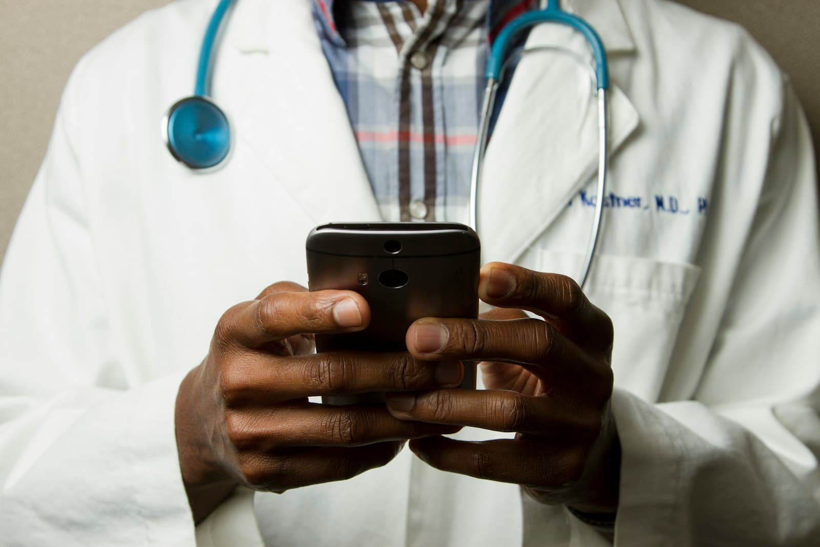 A clinician in a white coat using a smartphone