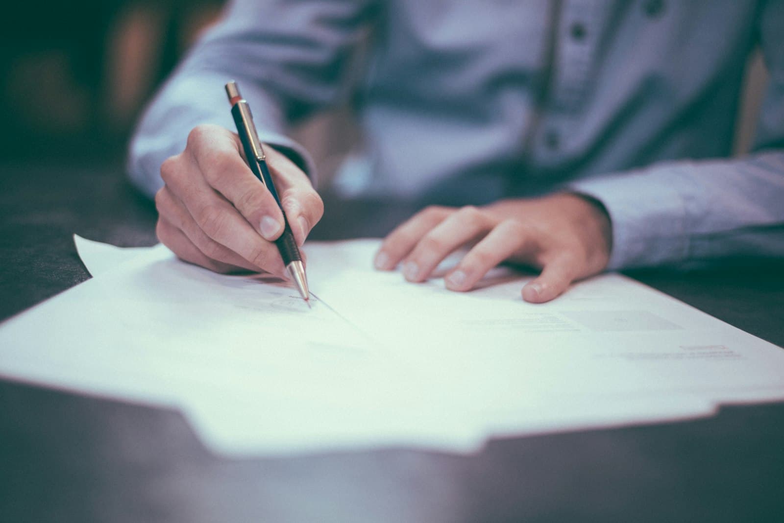 Photo: Scott Graham, Unsplash A person signing paperwork at a desk