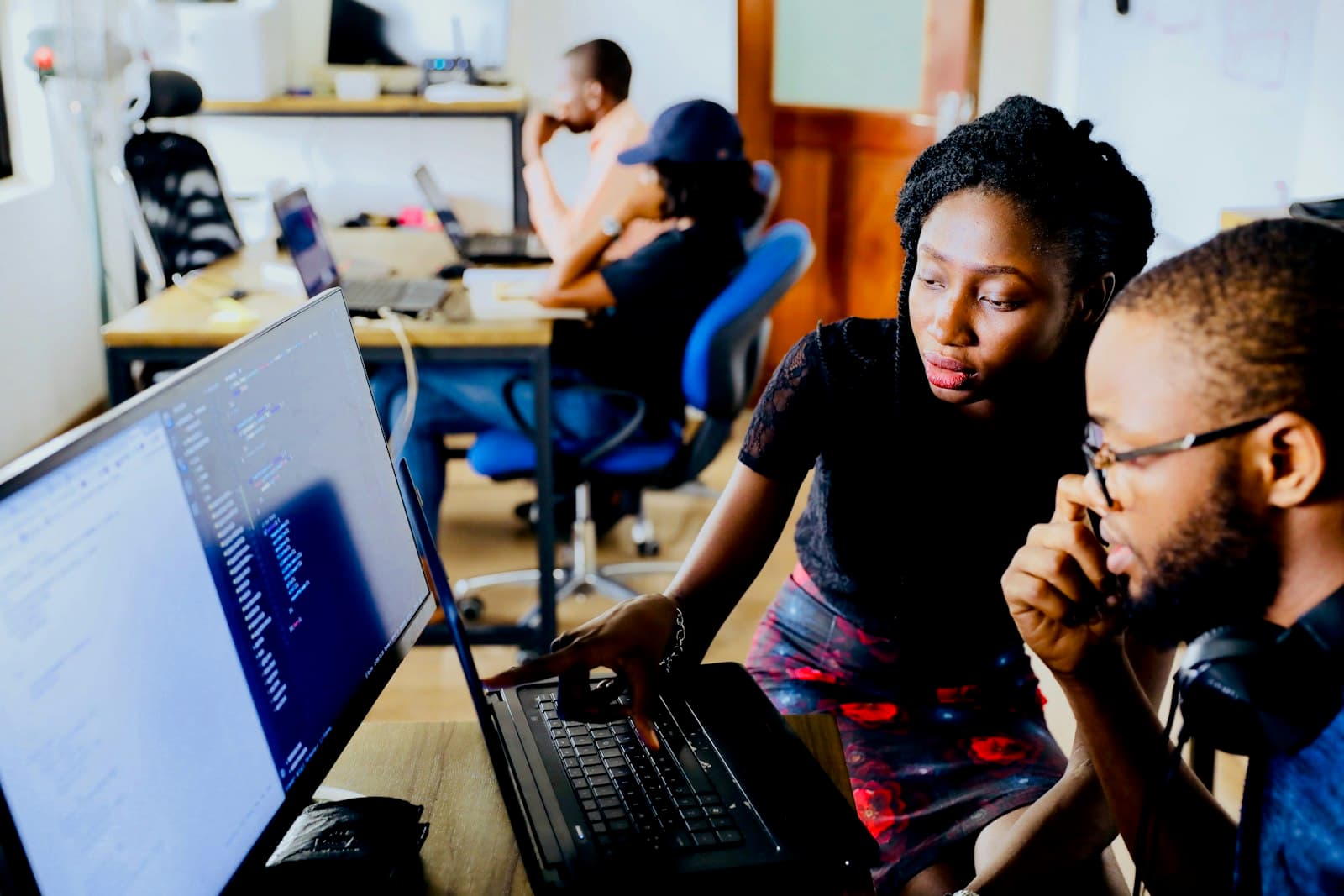 Photo: Unsplash Three colleagues gathered around a laptop, working through a problem together