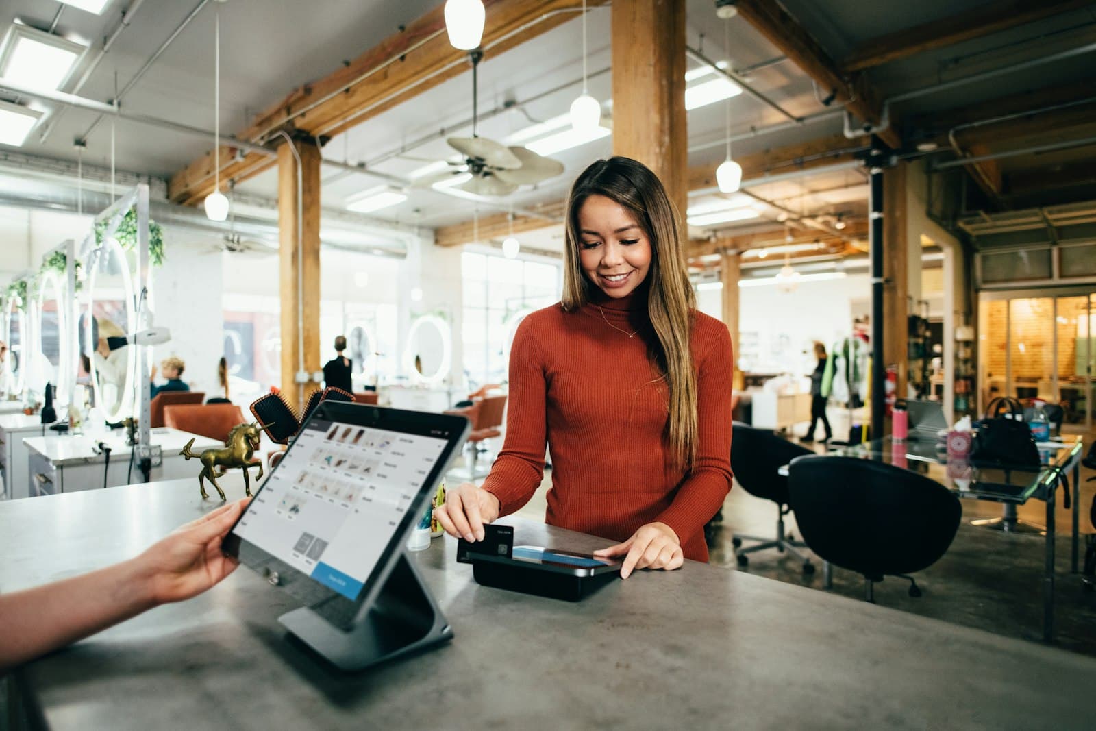 Photo: Blake Wisz, Unsplash A shop assistant at a counter taking a card payment