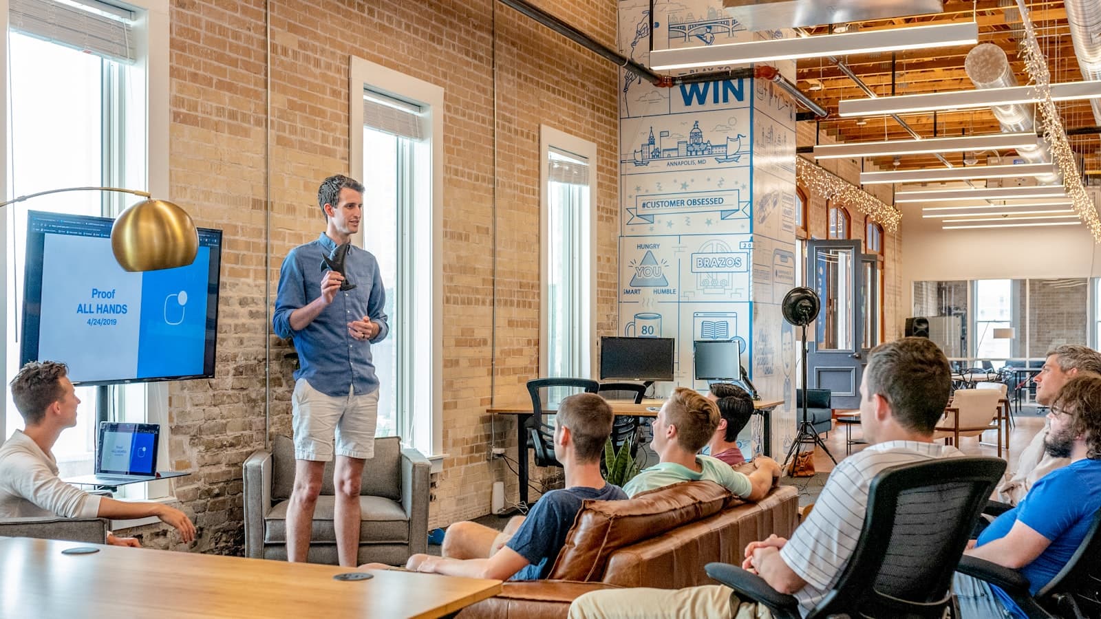 Photo: Austin Distel, Unsplash A person presenting to a small group in a loft office