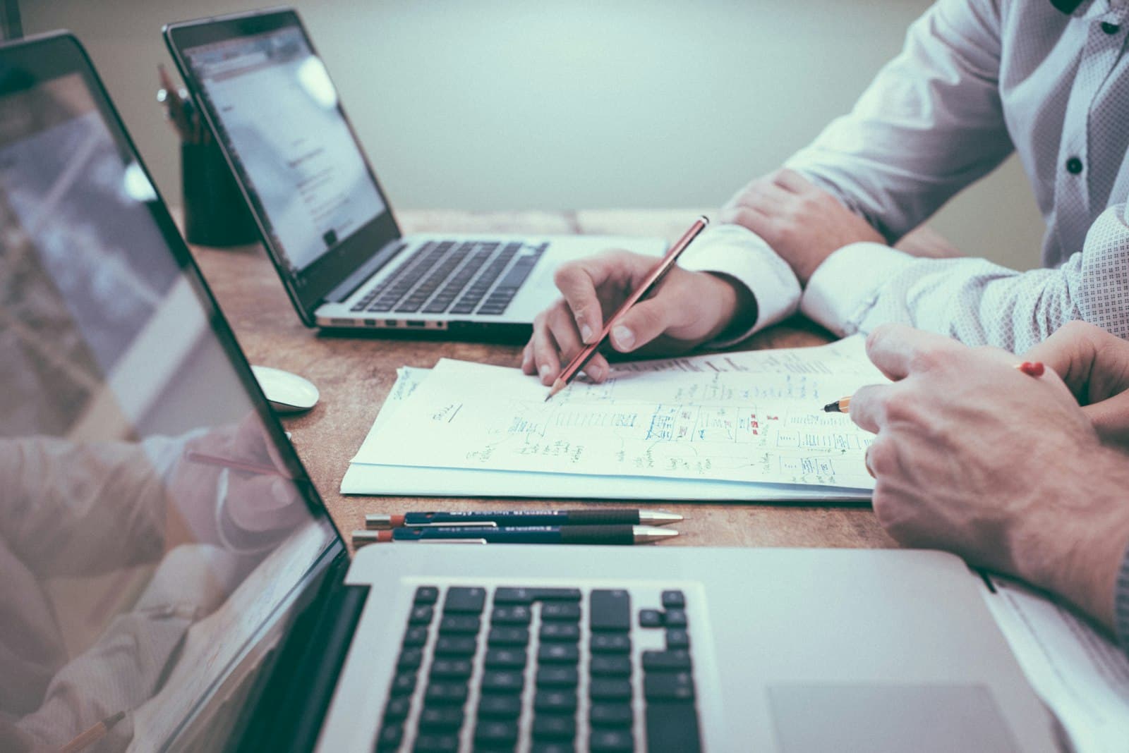 Photo: Scott Graham, Unsplash Two people sketching a plan on paper between two laptops